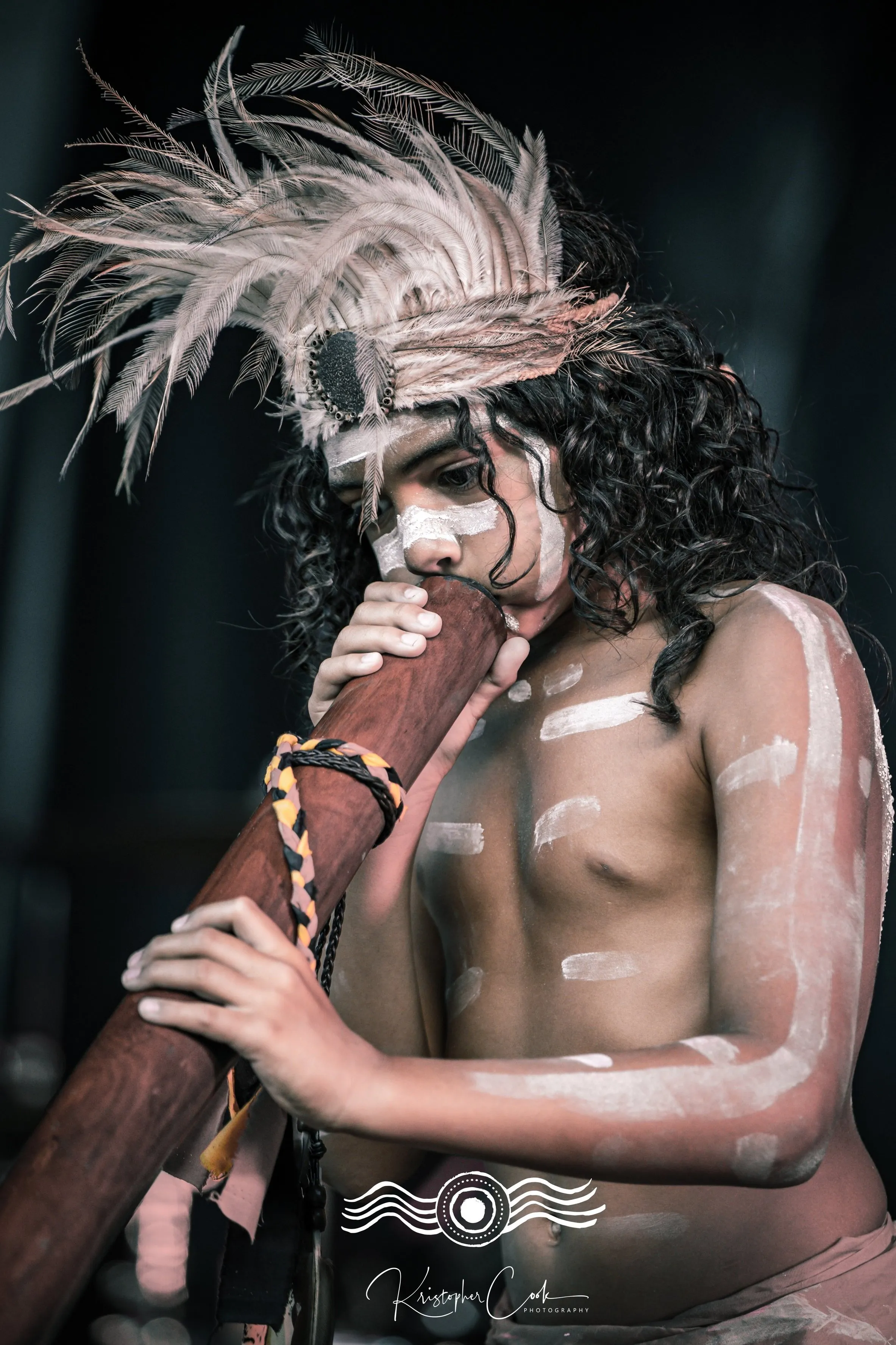 Didge player in ochre and feathers at Groove on the Grass, Grafton, 2023, photographed by Kris Cook