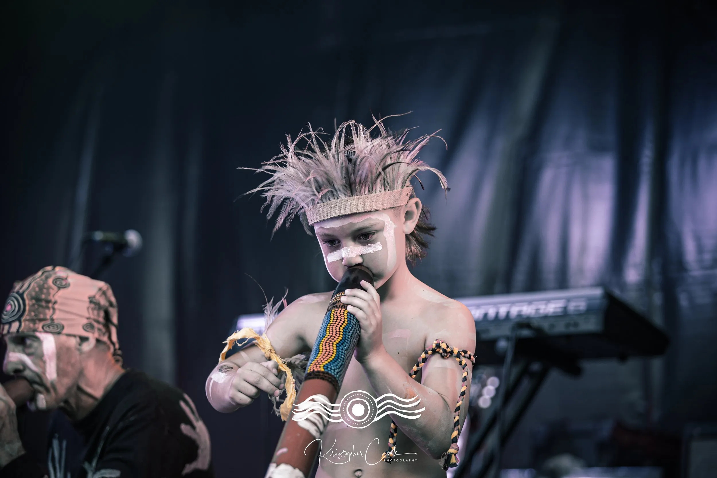 Young dancer in ochre singing on stage at Groove on the Grass, Grafton, 2023, photographed by Kris Cook